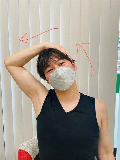 椅子に座って首の側面をストレッチする男性