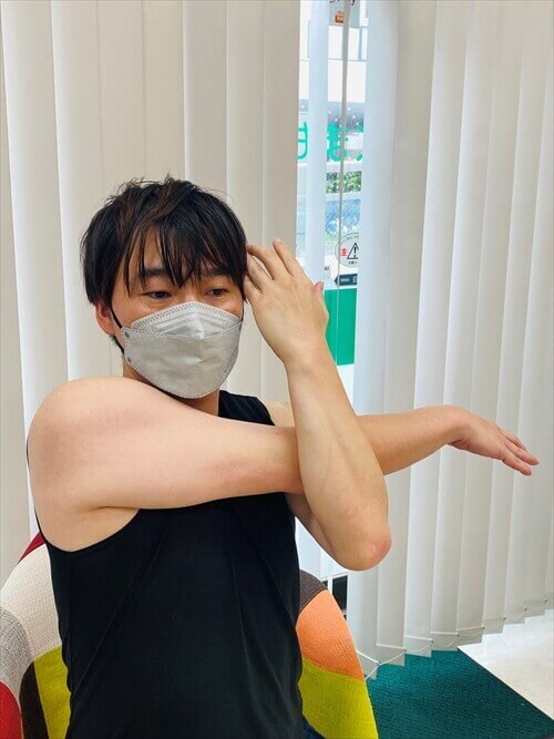 腕を前で伸ばして肩をストレッチする男性